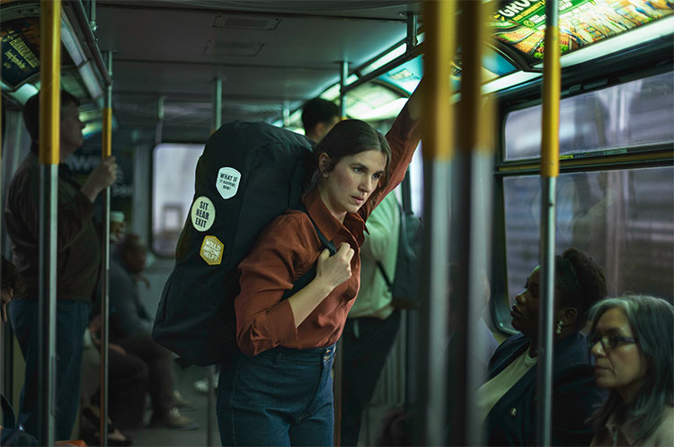 An adult carrying a heavy, oversized backpack representing her mental burden of being unprepared for episodes of frequent seizures while riding the subway